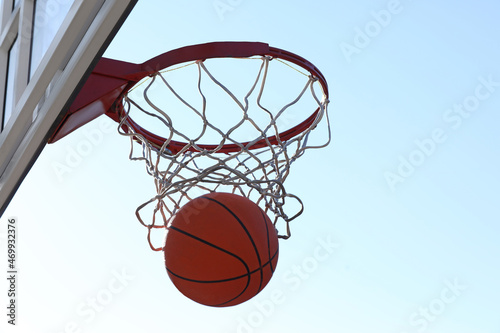Basketball ball and hoop with net outdoors on sunny day