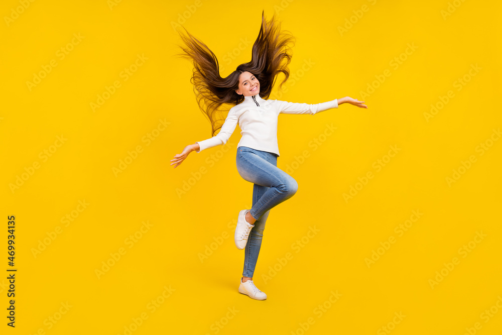Full size photo of pretty brunette teenager girl wear white sweater jeans shoes isolated on yellow color background