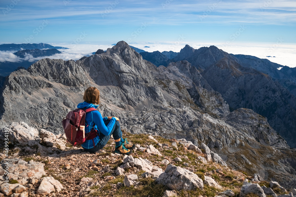 Female hiker sitting and relaxing on a mountain and enjoying beautiful view.