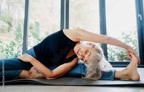 Yoga at home. Senior woman exercising indoor. Concept of healthy lifestyle.
