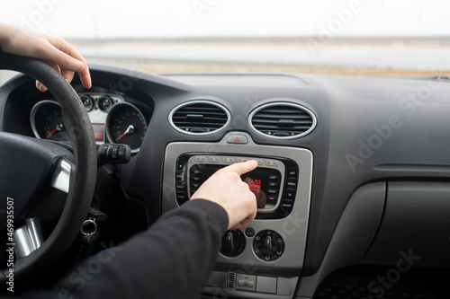 driver hand adjusting car multimedia, turn on radio © Mihail