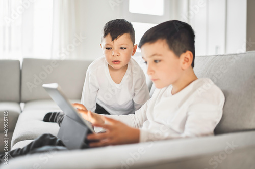 Childs relaxing with their tablets on a comfortable sofa at home