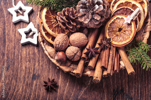 Fototapeta Naklejka Na Ścianę i Meble -  Dry orange, star anise, cinnamon, pine cones and fir tree in rustic plate on wooden table. Homemade medley idea for Christmas mood and aroma. Eco friendly christmas with homemade natural decorations.