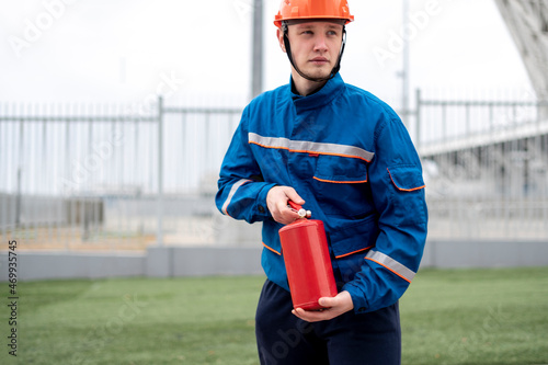 male undustrial worker in blue uniform and red helmet holding the red fire extinguisher photo