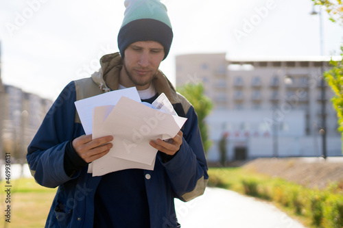 Billede på lærred male courier checking the paper documents outdoors, home goods delivery