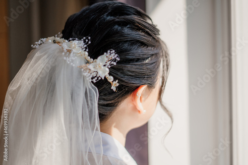 chinese woman wearing bridal veil in hotel room looking at the window