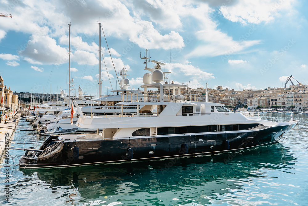 Luxury motorboats in Vittoriosa Yacht Marina.Sunny summer day.Holiday high-class lifestyle travel concept.Boat trip in Mediterranean.View of expensive sailing yachts at the pier. Posh deluxe vacation
