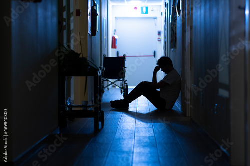Silhouette of sick and tired nurse or doctor into hospital\'s corridor during night shift.