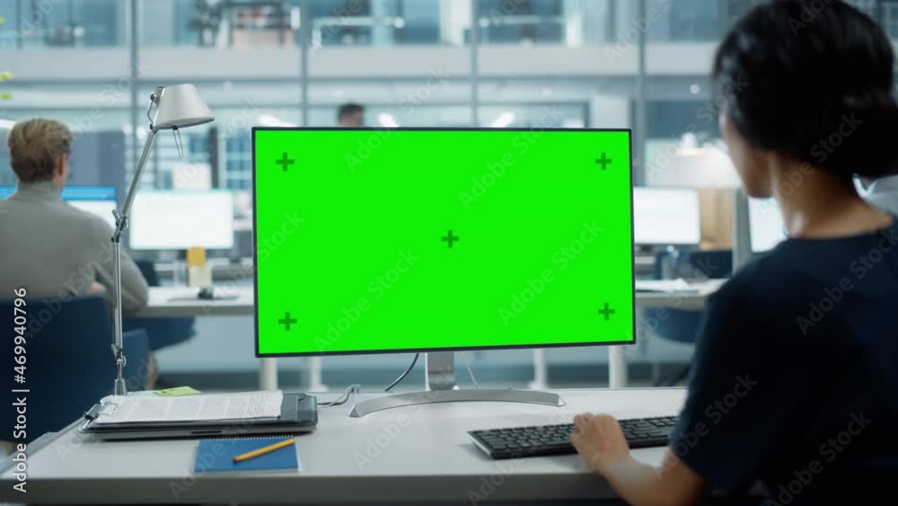 Close Up Over the Shoulder Shot of a Businesswoman Working on Desktop Computer with Chroma Key Green Screen Mock Up Display. Digital Projects Manager Typing Data, Using Keyboard and Mouse. Close Up Over the Shoulder Shot of a Businesswoman Working on Desktop Computer with Chroma Key Green Screen Mock Up Display. Digital Projects Manager Typing Data, Using Keyboard and Mouse.