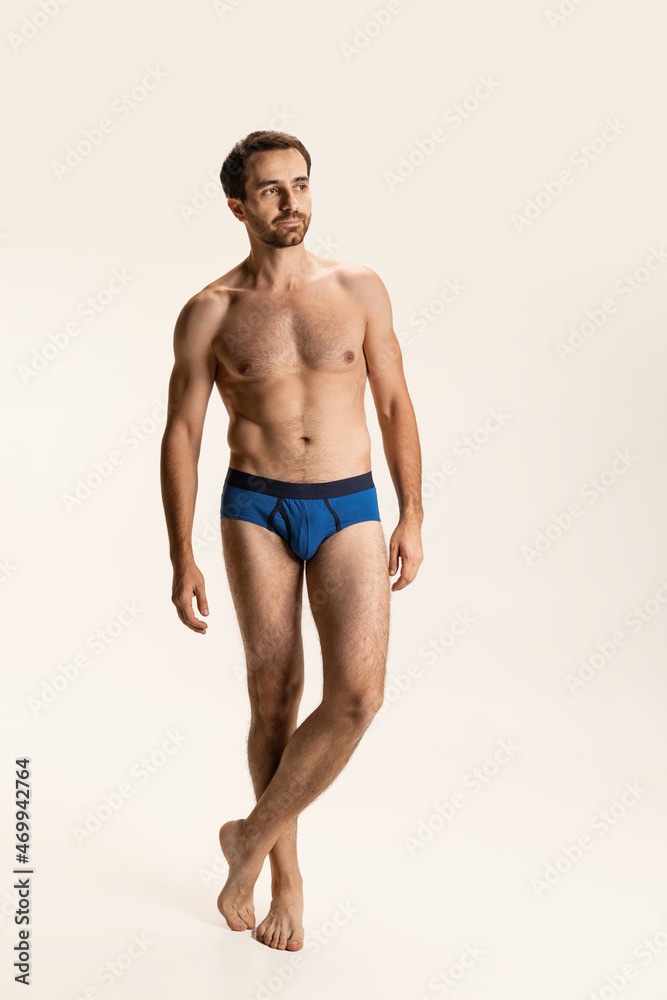 Full-length portrait of young handsome bearded shirtless man standing alone isolated on white studio background. Full-length portrait of young handsome bearded shirtless man standing alone isolated on white studio background.