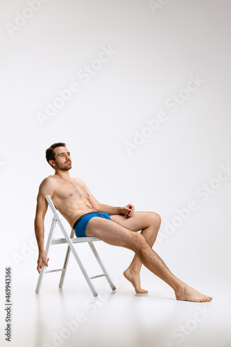 Wallpaper Mural Portrait of young handsome bearded shirtless man sitting on chair isolated on white studio background. Natural beauty Torontodigital.ca