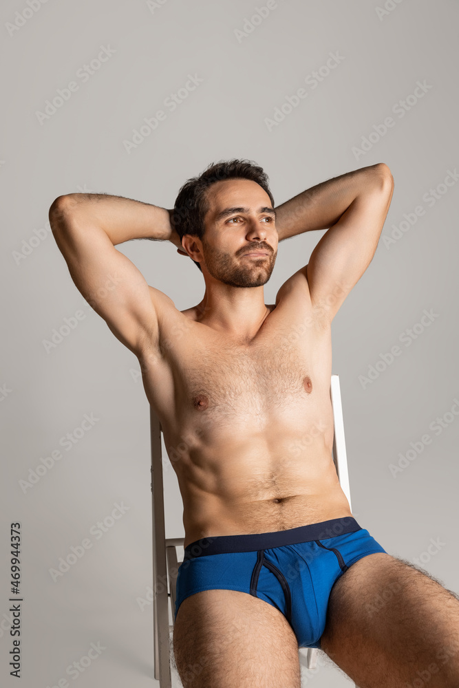Portrait of young handsome bearded shirtless man sitting and looking up isolated on gray studio background. Natural beauty Portrait of young handsome bearded shirtless man sitting and looking up isolated on gray studio background. Natural beauty