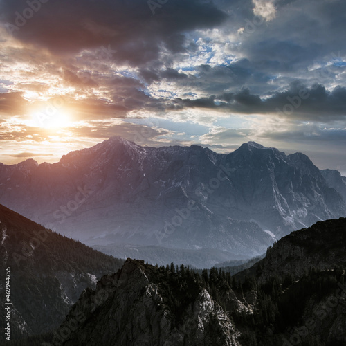 Amazing sunset landscape in the mountains. View of mountain range  stony slopes  rocky peaks in sunshine and dramatic cloudy sky at distance. Bavarian Alps. Europe. Nature concept  background. 