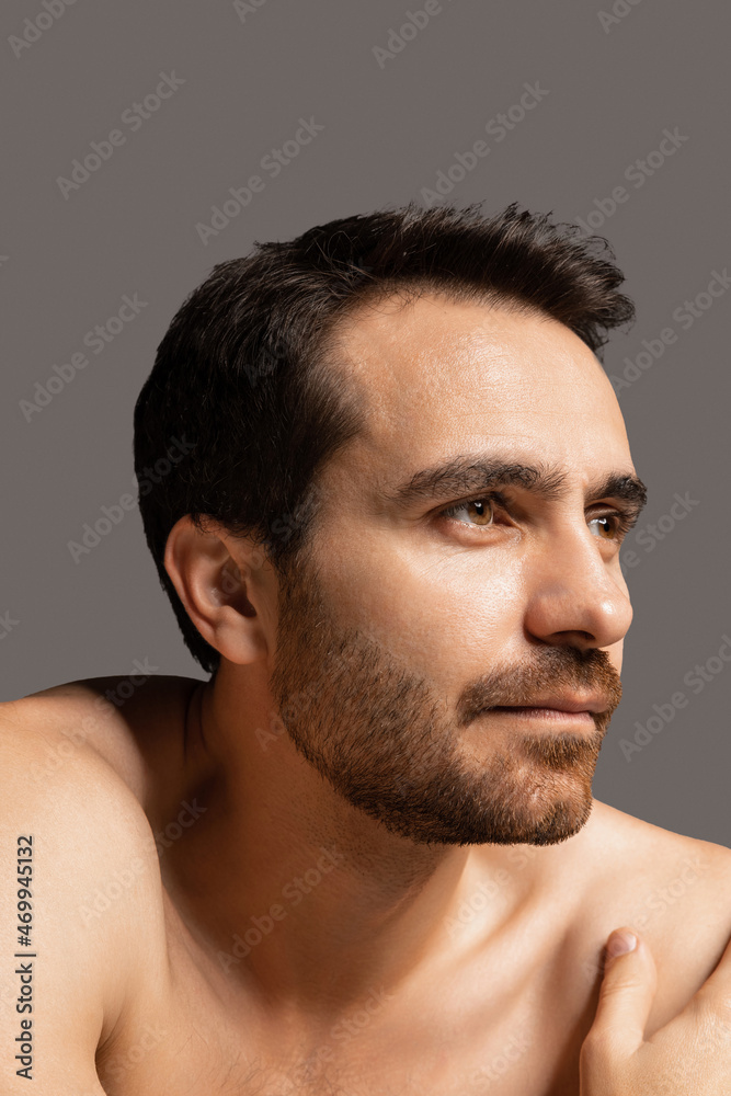Obraz premium Close-up portrait of young handsome bearded shirtless man isolated on gray studio background. Natural beauty