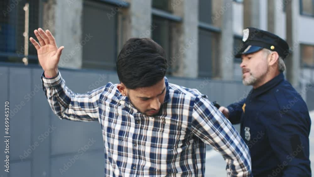 Cinematic police arrest with criminal led away in handcuffs. Policeman preparing to puts the handcuffs on the hands of criminal Cinematic police arrest with criminal led away in handcuffs. Policeman preparing to puts the handcuffs on the hands of criminal