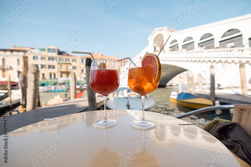 Two summer alcohol coctails on the table at outdoor cafe near Grand Canal and Rialto ridge in Venice. Italian Spritz Aperol drink at famous landmark in Italy