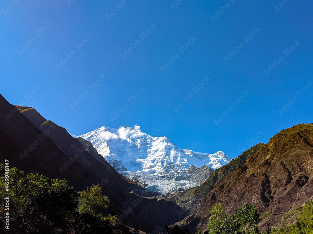 Obraz premium A Snow Capped Mountain Peak Seen Between Two Huge Mountains, Called Rakaposhi Peak, Located In Gilgit-Baltistan, Pakistan