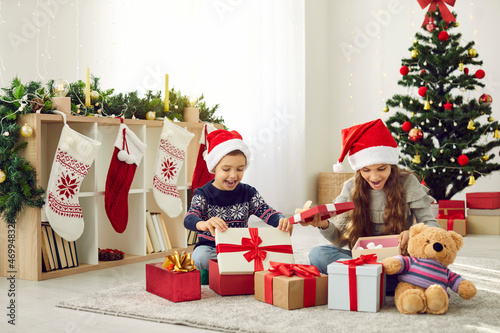 Quadro em tela Overjoyed small boy and girl kids have fun unpack wrapped boxes with presents on Christmas morning
