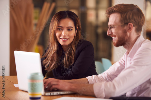 Business Colleagues With Laptop Having Informal Meeting Around Table In Office Coffee Shop