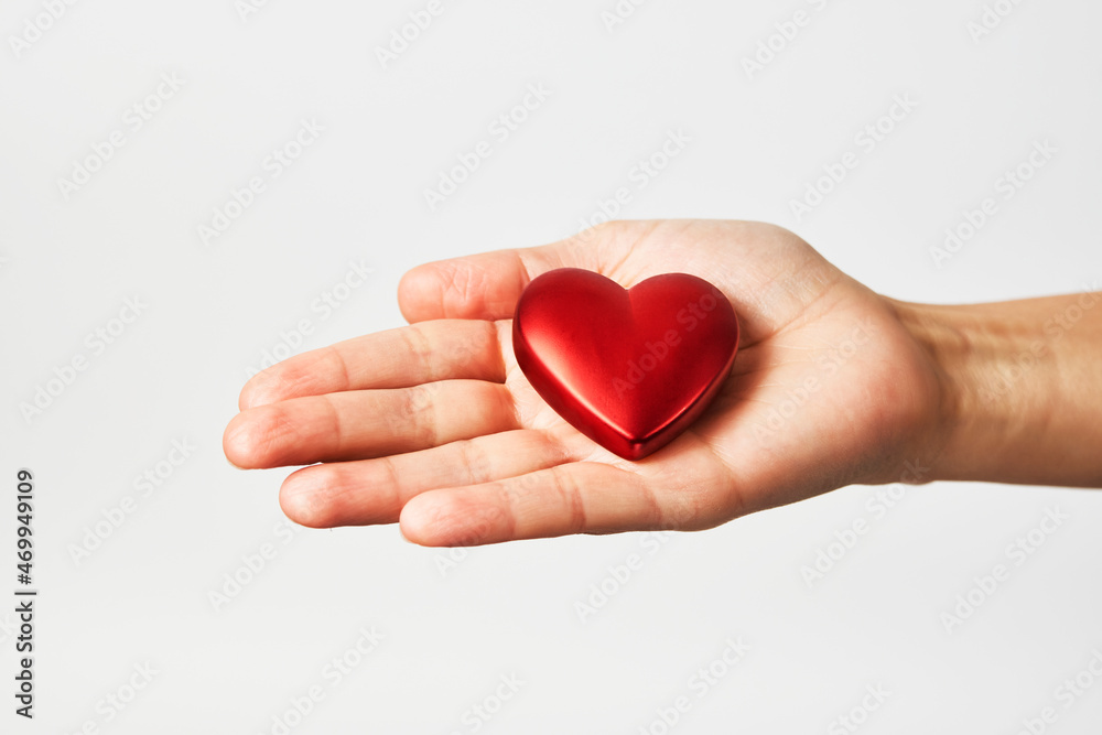 Hands holding red heart, close-up, white background Hands holding red heart, close-up, white background