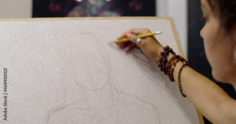Close up back view of female artist making sketch portrait with pencil indoors in studio home. Young woman student drawing studying art on professional easel. Hobby education profession concept