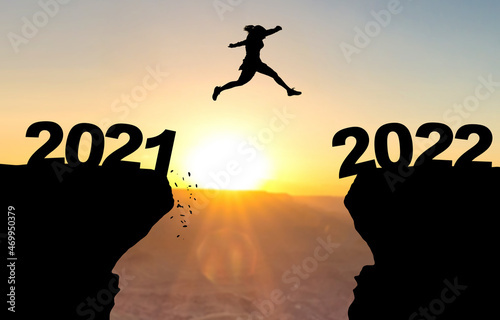 Woman jumps over abyss in front of sunset with the inscription 2021 and 2022.