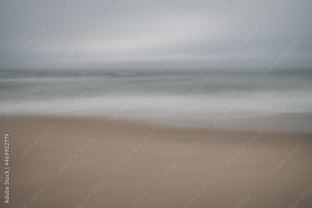 Soft focus beach foam rolls onto an empty beach during an Atlantic storm