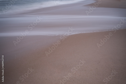 Soft focus beach foam rolls onto an empty beach during an Atlantic storm