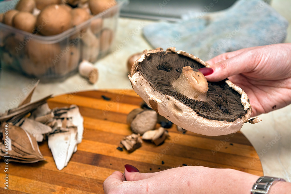 Model cooking in the kitchen and chopping the mushrooms for a mushroom cream