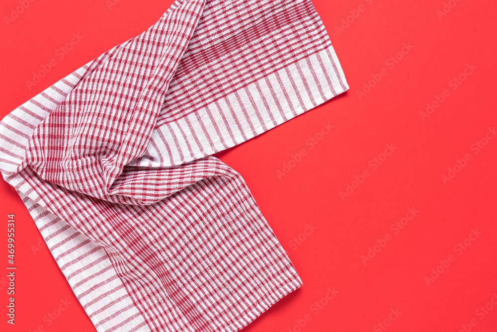 Red checkered kitchen napkin on a red paper background. Top view, flat lay.