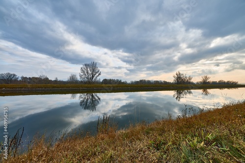 Autumn cloudy day with dramatic sky. Landscape with waterway and reflections of clouds on the water surface.  Trencin  Slovakia.