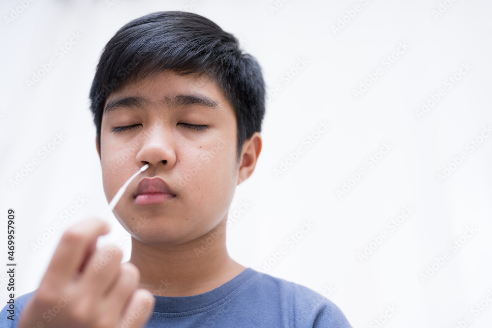 Asian boy self collecting nose swab for corona virus sample.Covid-19 laboratory test.Antigen test kit for rapid nose swab.Nasal swab is a test that takes a sample of cells from the nasopharynx. Asian boy self collecting nose swab for corona virus sample.Covid-19 laboratory test.Antigen test kit for rapid nose swab.Nasal swab is a test that takes a sample of cells from the nasopharynx.