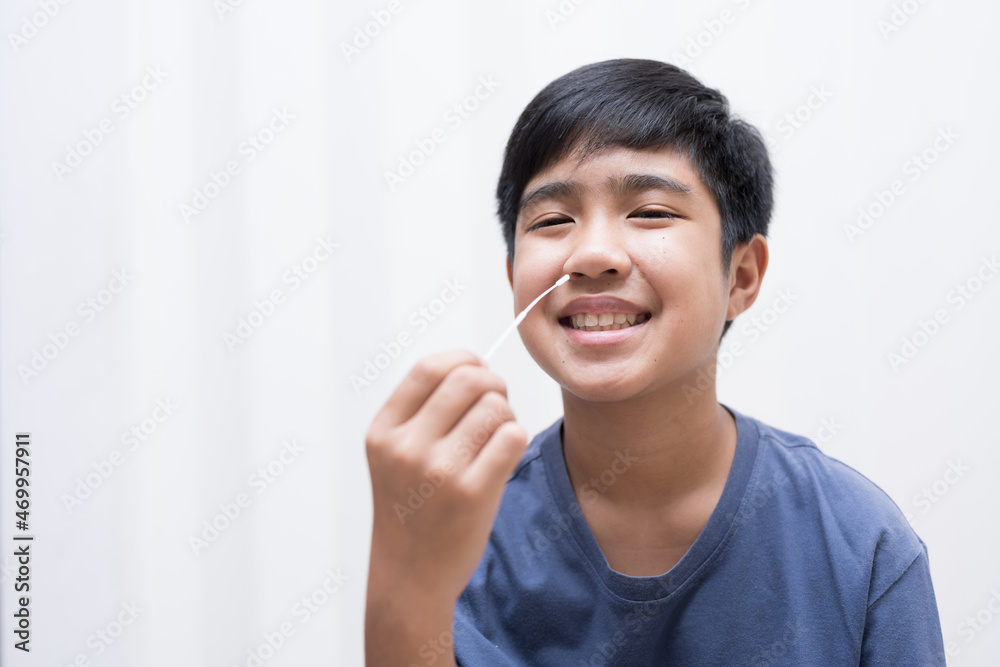 Asian boy self collecting nose swab for corona virus sample.Covid-19 laboratory test.Antigen test kit for rapid nose swab.Nasal swab is a test that takes a sample of cells from the nasopharynx. Asian boy self collecting nose swab for corona virus sample.Covid-19 laboratory test.Antigen test kit for rapid nose swab.Nasal swab is a test that takes a sample of cells from the nasopharynx.