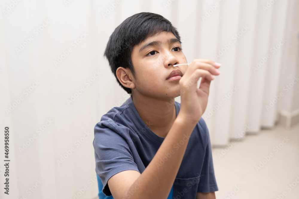 Asian boy self collecting nose swab for corona virus sample.Covid-19 laboratory test.Antigen test kit for rapid nose swab.Nasal swab is a test that takes a sample of cells from the nasopharynx. Asian boy self collecting nose swab for corona virus sample.Covid-19 laboratory test.Antigen test kit for rapid nose swab.Nasal swab is a test that takes a sample of cells from the nasopharynx.