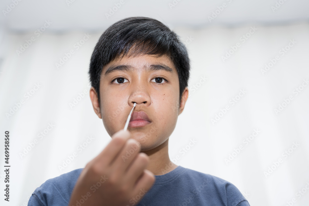 Asian boy self collecting nose swab for corona virus sample.Covid-19 laboratory test.Antigen test kit for rapid nose swab.Nasal swab is a test that takes a sample of cells from the nasopharynx. Asian boy self collecting nose swab for corona virus sample.Covid-19 laboratory test.Antigen test kit for rapid nose swab.Nasal swab is a test that takes a sample of cells from the nasopharynx.