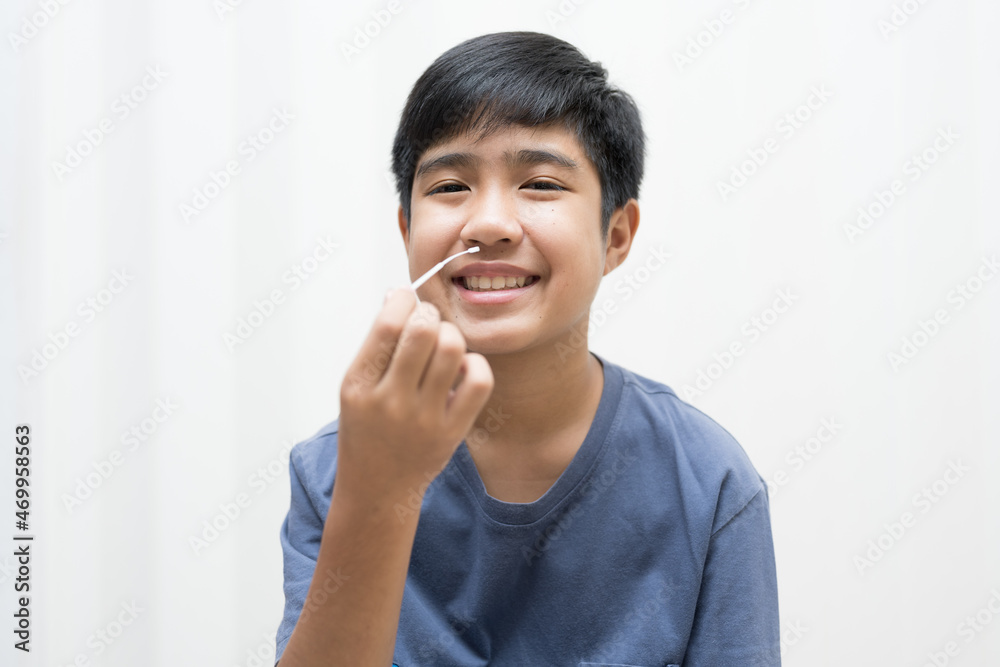 Asian boy self collecting nose swab for corona virus sample.Covid-19 laboratory test.Antigen test kit for rapid nose swab.Nasal swab is a test that takes a sample of cells from the nasopharynx. Asian boy self collecting nose swab for corona virus sample.Covid-19 laboratory test.Antigen test kit for rapid nose swab.Nasal swab is a test that takes a sample of cells from the nasopharynx.