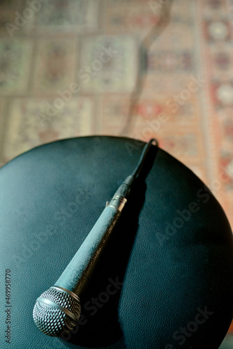 an old wired microphone lies on a round chair before performing on stage
