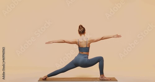 Yoga workout. Back view of young woman fitness instructor doing Peaceful Warrior Pose. Body and mind care concept