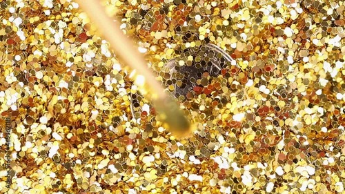 the brush from the macromech slowly moves to the one euro coin covered with gold dust and cleans the logo from above