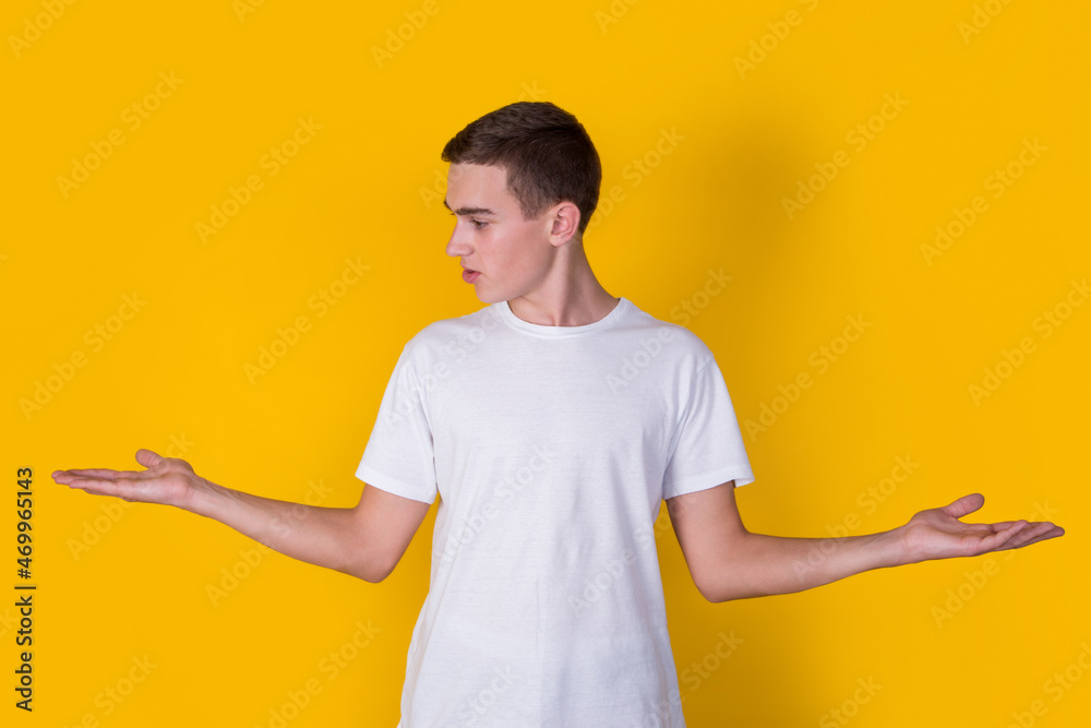 A handsome guy in a white t-shirt showing smth on a yellow background A handsome guy in a white t-shirt showing smth on a yellow background