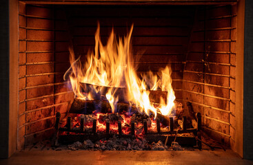 Christmas time, cozy fireplace. Wood logs burning, fire bricks background, relaxation and warm home
