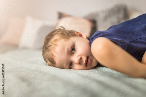 Half body of small blonde boy laying down on bed  photo