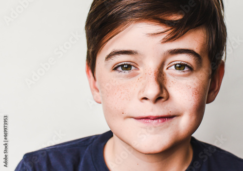 Close up portrait of cute young boy with brown hair and freckles.