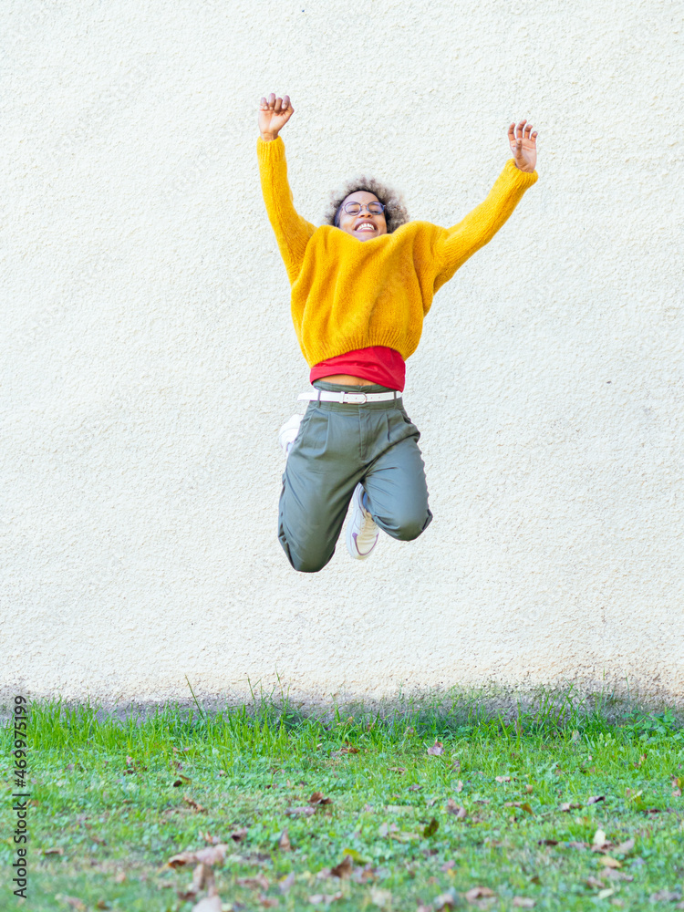 Cheerful African American woman jumping for joy in a park Cheerful African American woman jumping for joy in a park