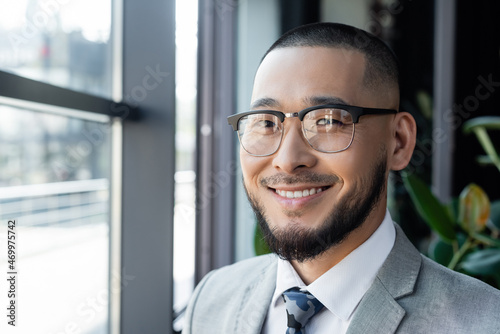 bearded asian businessman in eyeglasses smiling at camera in office © LIGHTFIELD STUDIOS