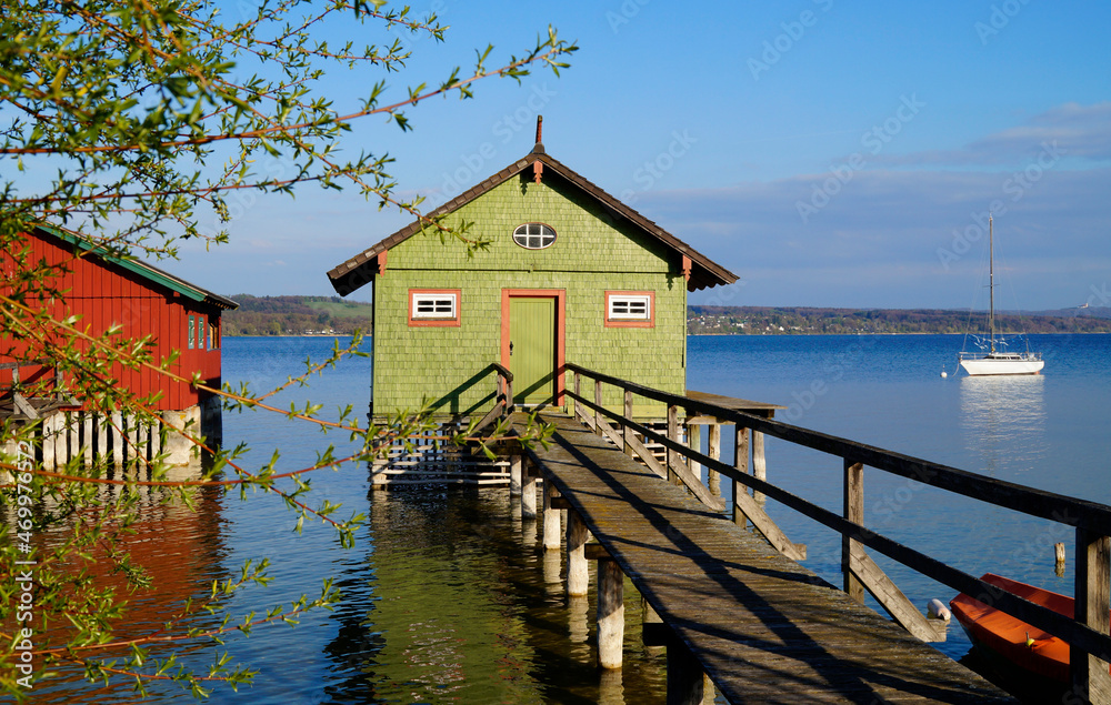 a long wooden pier leading to the colorful boat houses on lake Ammersee in the German fishing village Schondorf (Germany)	
