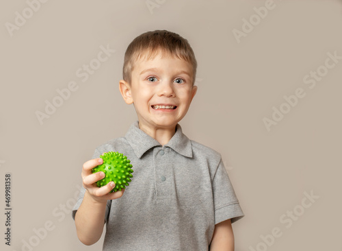Cheerful child performs an exercise with a relief ball to develop tactile sensations. Exercise for the development of fine motor skills of the hands.Selective focus