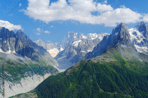 high mountains  rocky cliffs with trees  in the background you can see the French Alps with the snow-capped Mont Blanc  the concept of hiking  rock climbing  active lifestyle  beauty of nature