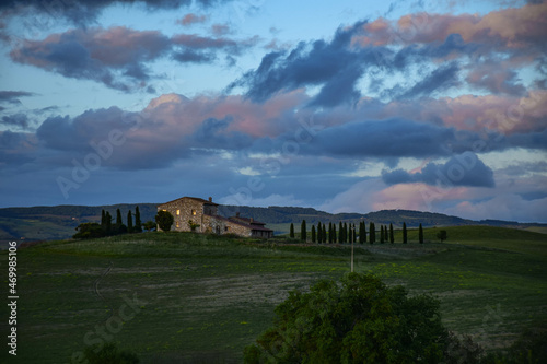 Tuscany  Italy 2019  a farm on a green hill with a cypress alley against the backdrop of a sunset sky