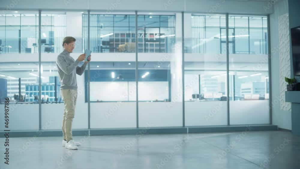 Handsome Stylish Interior Designer Standing in Empty Modern Office and Map it with an Augmented Reality Software on a Tablet Computer. Architect Planning Out the Floor for Business Company Space. Handsome Stylish Interior Designer Standing in Empty Modern Office and Map it with an Augmented Reality Software on a Tablet Computer. Architect Planning Out the Floor for Business Company Space.